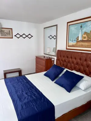 a bedroom with a large bed with blue pillows at El Laguito, Edificio El Conquistador in Cartagena de Indias