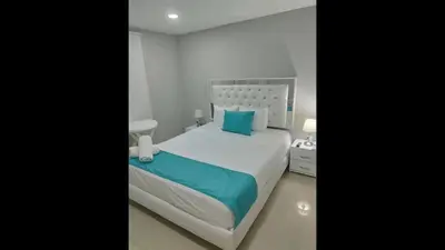 a bedroom with a large white bed with blue pillows at Cozy room Bm-10 near the sea with air conditioning and WIFI in Cartagena de Indias
