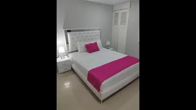 a bedroom with a white bed and a pink pillow at Bm-8 room near the sea with air conditioning and WIFI in Cartagena de Indias
