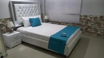 a bedroom with a large white bed with blue pillows at Bm-3 room near the sea with air conditioning and WIFI in Cartagena de Indias