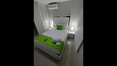 a small bed in a small room with a green blanket at Bm-13 room near the sea with air conditioning and WIFI in Cartagena de Indias