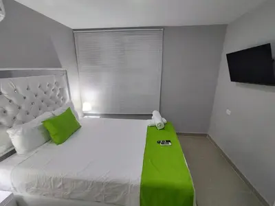 a bedroom with a bed with a green blanket on it at Bm-13 room near the sea with air conditioning and WIFI in Cartagena de Indias