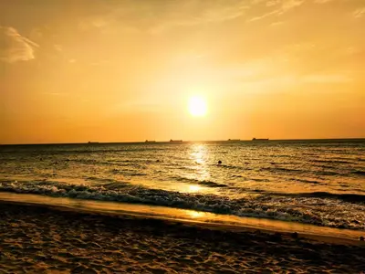 a beach with the sun setting over the ocean at Playa Dormida 2. Hermoso apartamento frente al mar in Santa Marta